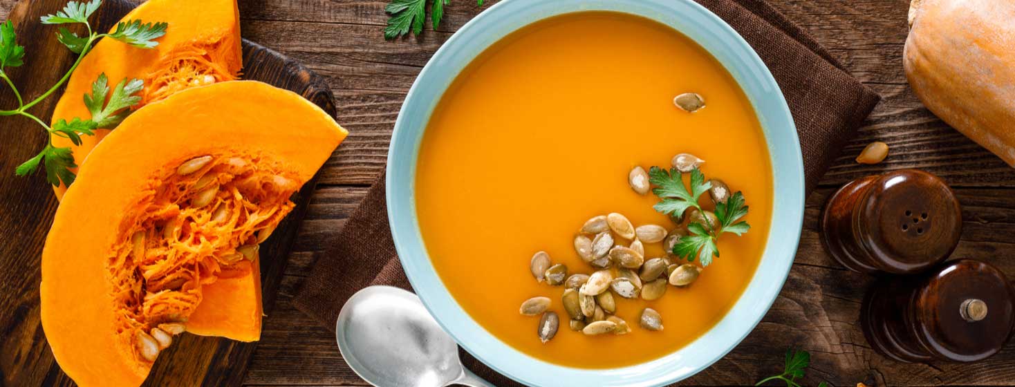 Vegetarian soup with pumpkin seeds in bowl on wooden table