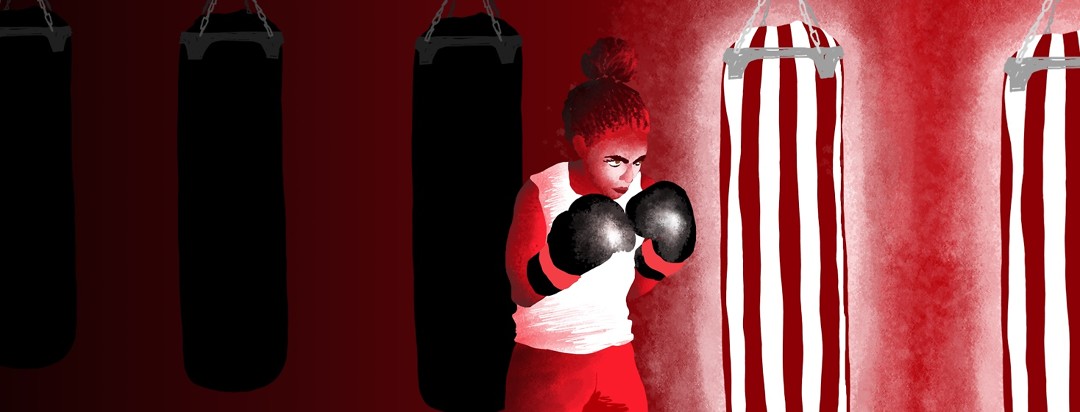 A female boxer determinately approaches a glowing punching bag.