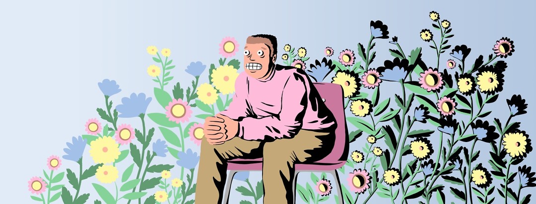 A nervous man sits against a background of flowers. Both the man and the flowers are more significantly in shadow on the right than on the left.