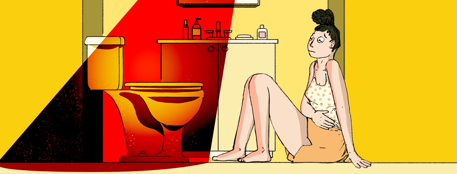 A woman sits uncomfortably on the bathroom floor with her hand over her stomach and staring warily at the toilet in front of her which is illuminated by an evil red light.