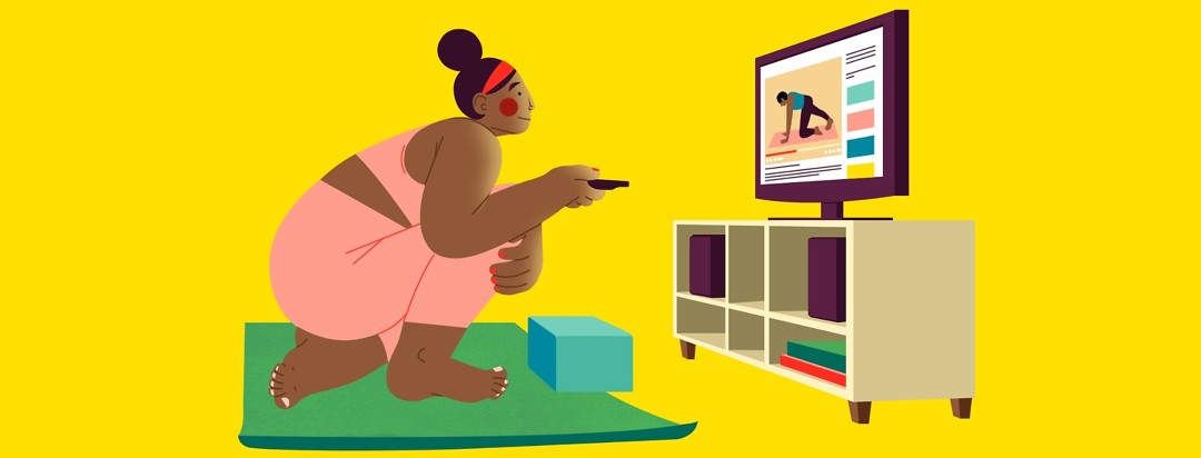A woman crouches over a yoga mat, holding a TV remote as she chooses a yoga YouTube tutorial to watch on her TV, which is sitting on a TV stand in front of her.