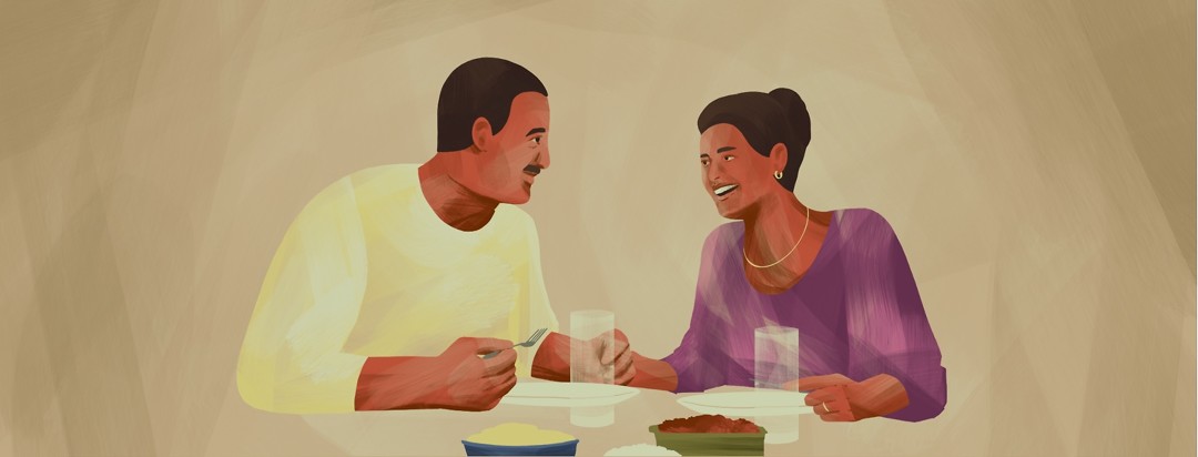A couple happily eats dinner together.