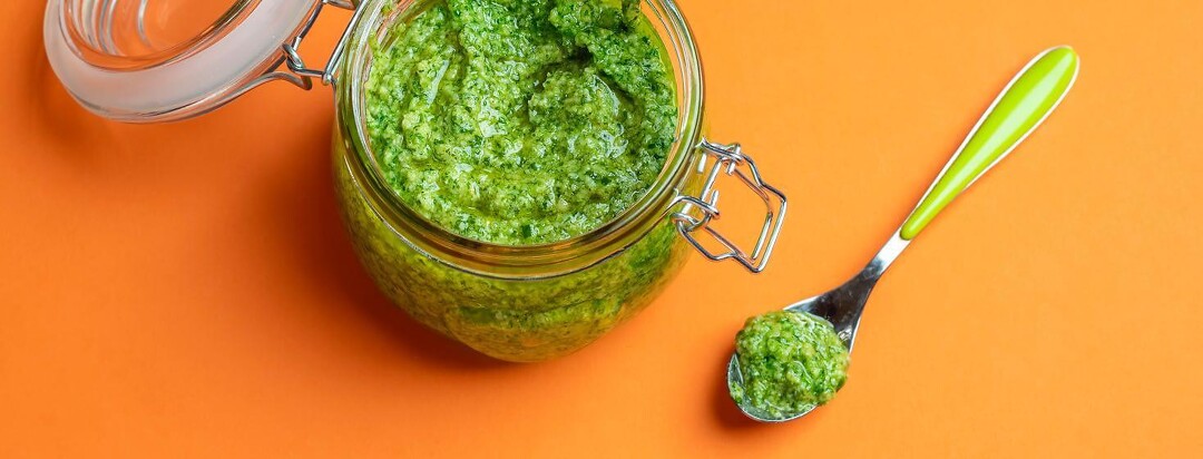 A jar of carrot top pesto and spoon