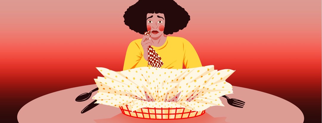 A woman dabs a napkin at the corner of her mouth, looking suddenly worried and shocked. An empty basket of food lays before her.