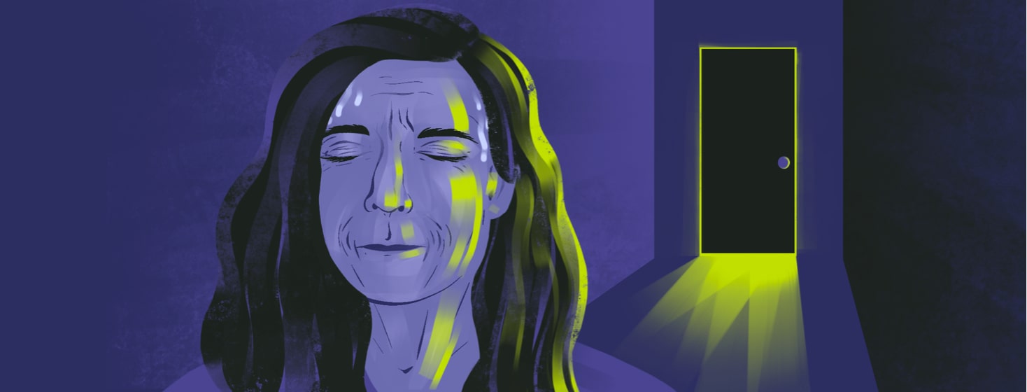 alt=a woman squeezes her eyes shut and bites her lip, sweating while facing away from a close door emitting light around the outline