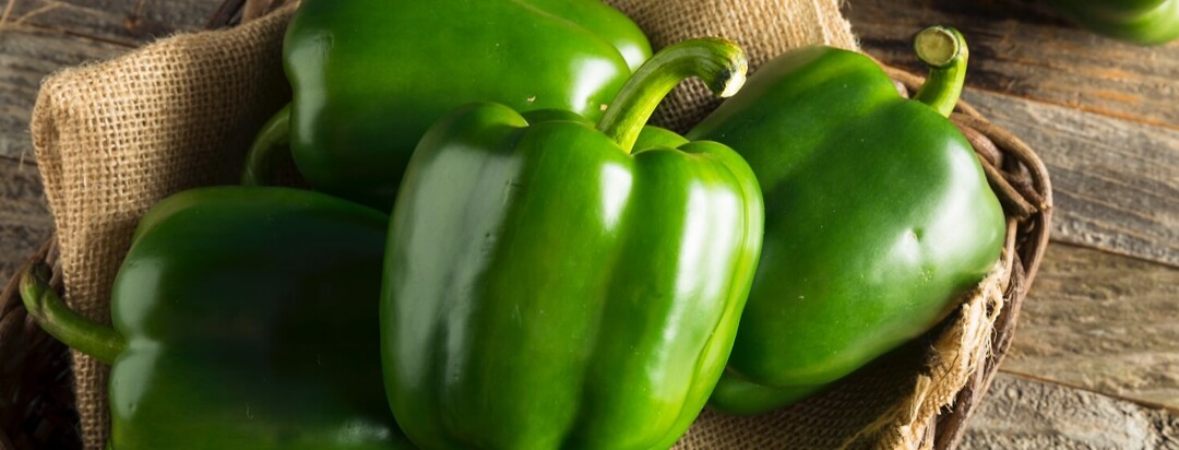 Green bell peppers held in a brown basket