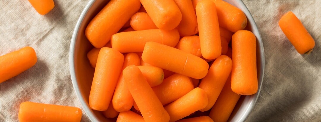 baby carrots in a white bowl on table