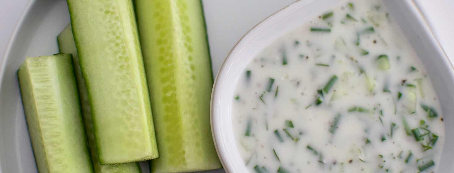 Sliced cucumber and a bowl of IBS friendly Tzatziki
