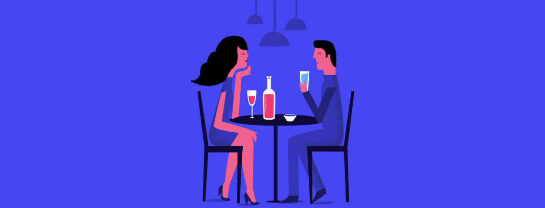 A man and a woman sitting at a table enjoying dinner and the woman has a glass of wine and the man a glass of water.